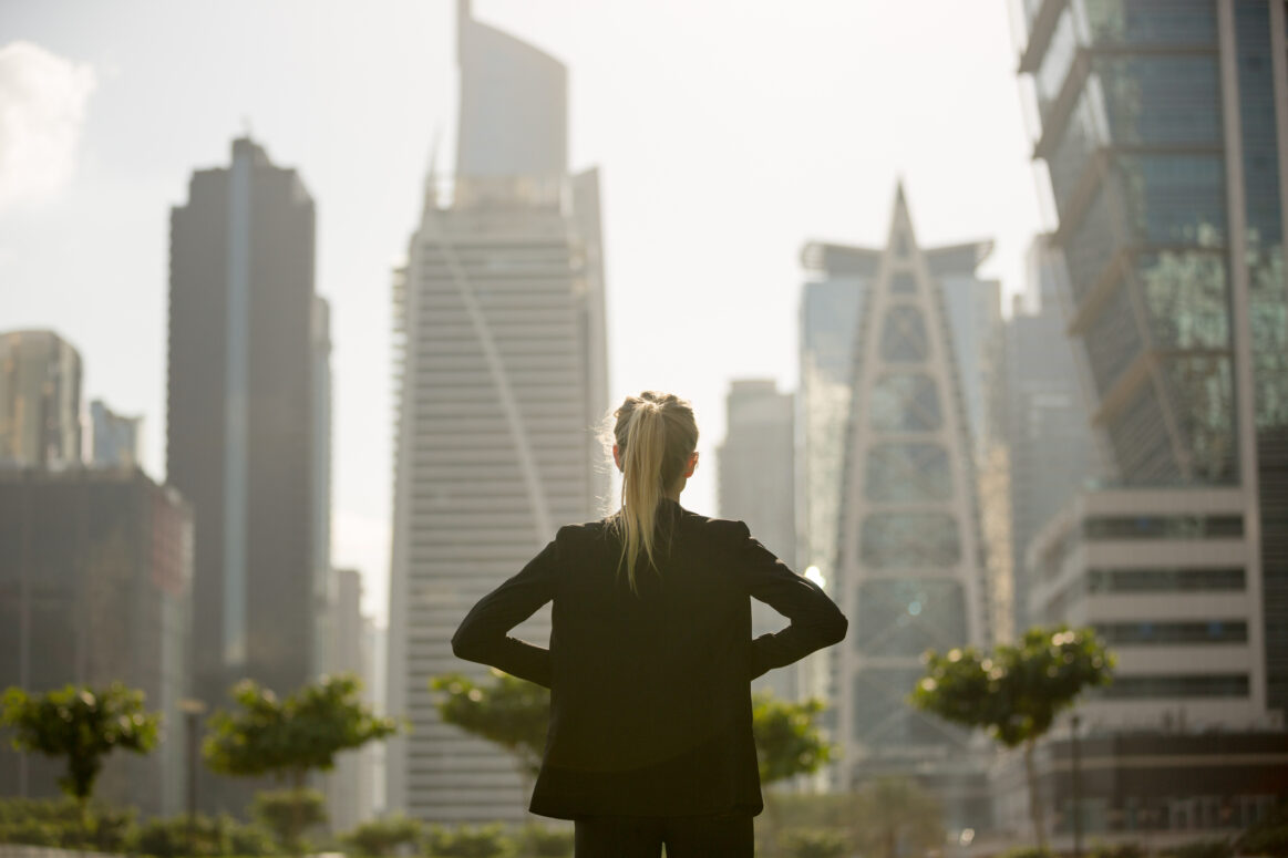 Confident business woman standing strong looking at the city high-rises view. Business ambition and aspiration.
