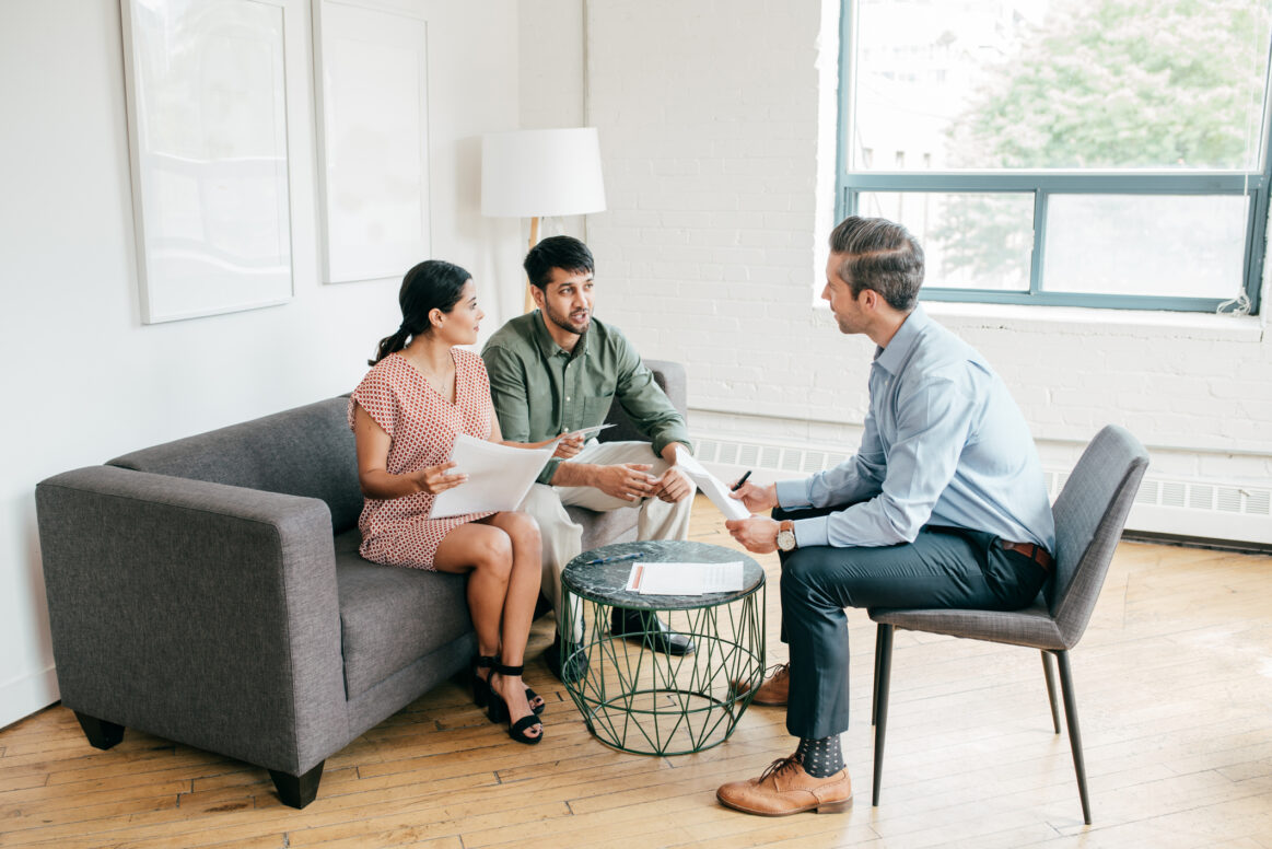 A real estate agent sits down with two clients to discuss options