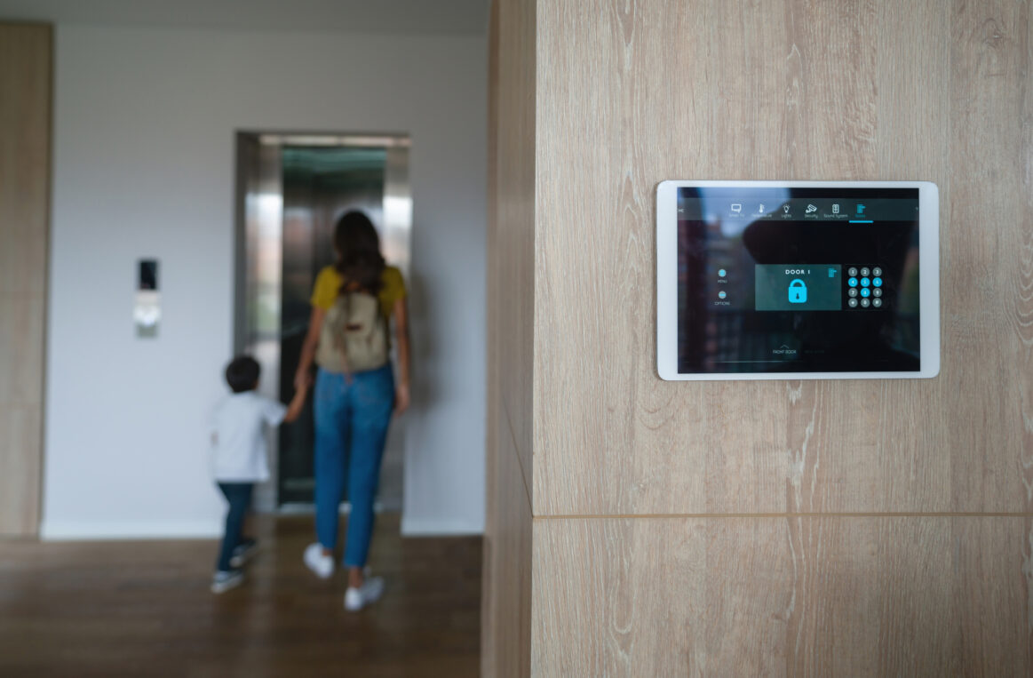 Latin American mother and son leaving the house and locking the door using an automated security system - focus on foreground.