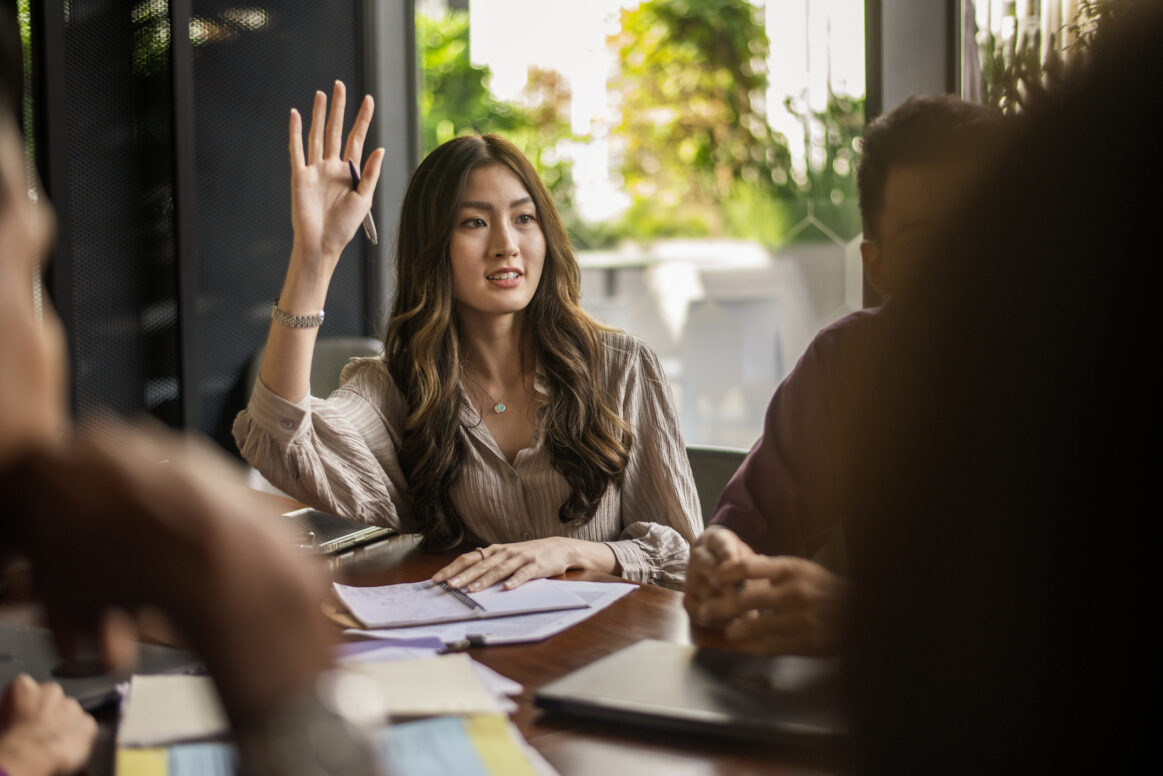 Photos Business lady raising hand and asking a question during a discussion
