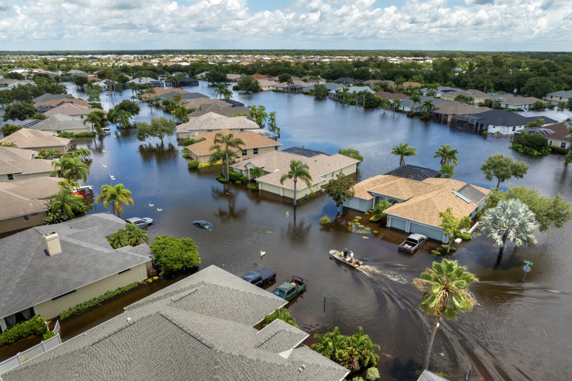Aftermath of hurricane Debby flooding natural disaster. Boat floating on flooded street surrounded by tropical storm rainfall flood waters homes in Sarasota, Florida residential area.